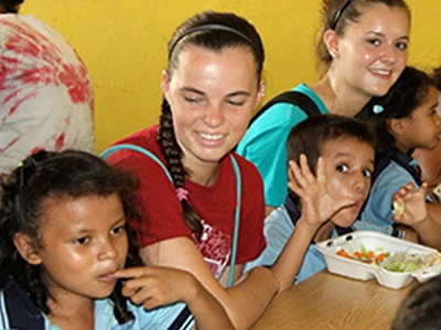 Female Student Eating With Kids